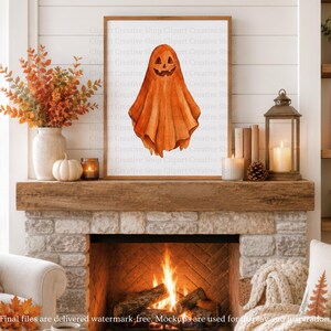 Puede incluir: Una l&aacute;mina de arte enmarcada con una ilustraci&oacute;n en acuarela de un fantasma con cabeza de calabaza tallada. El fantasma es de color naranja con una cara de calabaza sonriente y textura de tela drapeada, centrado en un marco de madera sencillo.