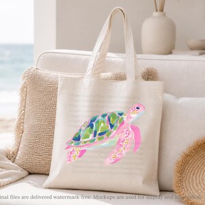 May include: A cream tote bag with a watercolour sea turtle design. The turtle has a pink head and flippers, a green and blue shell, and is set against a beach scene. The bag has long handles.