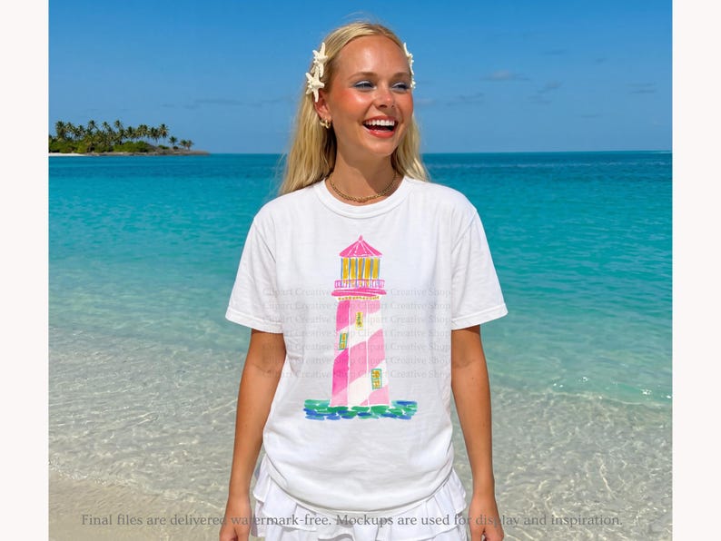 K&ouml;nnte beinhalten: Wei&szlig;es T-Shirt mit einer Aquarellillustration eines rosa und wei&szlig; gestreiften Leuchtturms mit gelbem Dach. Das T-Shirt wird von einer Person an einem Strand mit t&uuml;rkisfarbenem Wasser und blauem Himmel getragen. Der Text "Final files are delivered watermark-free. Mockups are used for display and inspiration."