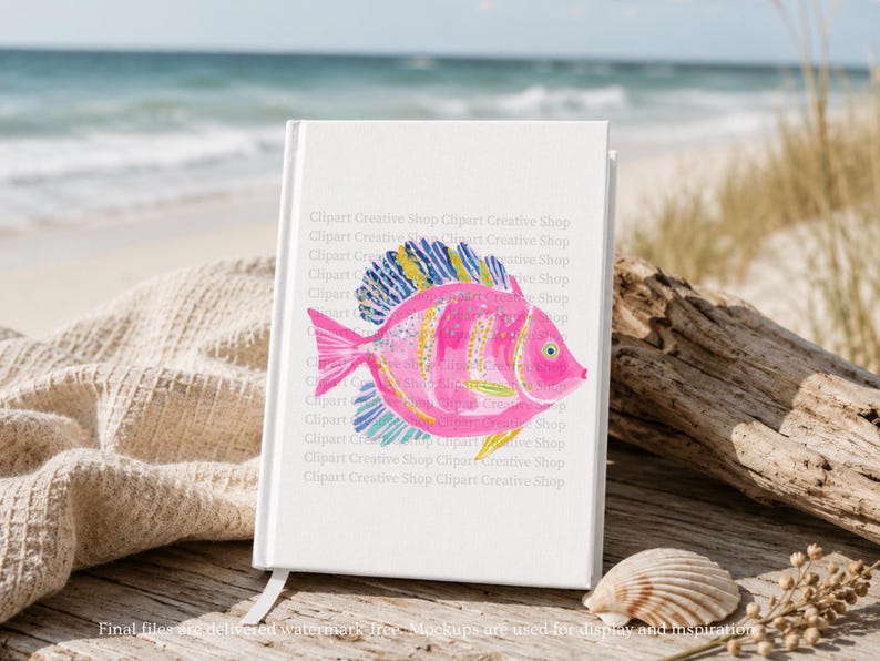 K&ouml;nnte beinhalten: Ein wei&szlig;es Notizbuch mit festem Einband und einer leuchtend rosa Fischillustration auf dem Cover. Der Fisch hat gelb-blau gestreifte Flossen, ein gelbes Auge und goldfarbene Akzente. Der Text Clipart Creative Shop ist im Hintergrund wiederholt.