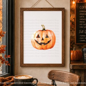 May include: A framed wall art print featuring a watercolor illustration of an orange jack-o'-lantern pumpkin with a carved face. The artwork is displayed in a dark brown wooden frame hanging on a wall, showcasing a festive autumn theme.
