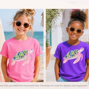 May include: Two young girls wearing sunglasses and t-shirts with a watercolour sea turtle design. One shirt is pink, the other is purple. A surfboard with the words "GOOD VIBES" is in the background.