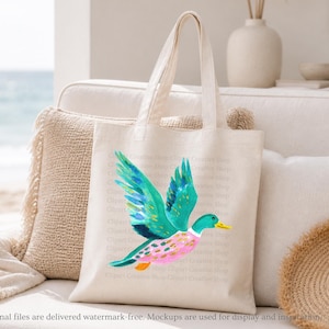 Op de afbeelding: Een cr&egrave;mekleurige canvas draagtas met een levendige aquarelillustratie van een vliegende wilde eend. De eend heeft heldere groenblauwe vleugels met gouden accenten, een groene kop, een gele snavel en een roze lichaam met oranje markeringen.