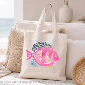 K&ouml;nnte beinhalten: Eine cremefarbene Canvas-Tragetasche mit einer lebendigen Aquarellillustration eines tropischen Fisches. Der Fisch ist haupts&auml;chlich leuchtend rosa mit gelb-blau gestreiften Flossen und einem gelben Schwanz. Die Tasche hat zwei stabile Tragegriffe.