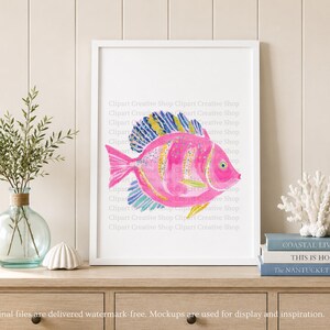 K&ouml;nnte beinhalten: Ein gerahmter Kunstdruck mit einer Aquarell-Illustration eines leuchtend rosa Fisches mit gelb und blau gestreiften Flossen. Der Fisch hat ein deutliches Auge und Schuppen und ist in einem wei&szlig;en Rahmen vor einer hellen Wand platziert.