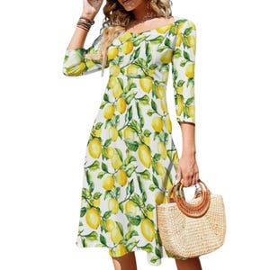 May include: A white, knee-length dress with a lemon print. The dress has three-quarter sleeves and a scoop neckline. A straw handbag with wooden handles is held in the hand. The dress is decorated with yellow lemons and green leaves.