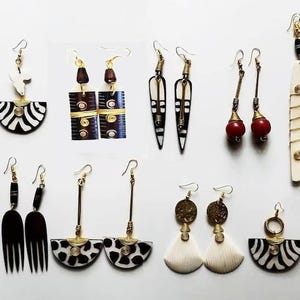 May include: A collection of handcrafted earrings with diverse designs. Styles include black and white zebra patterns, geometric shapes, and red bead accents. Materials appear to be wood, bone, and metal.