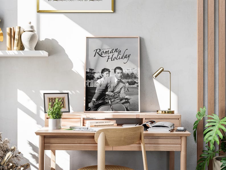 Może przedstawiać: Czarno-biały plakat z tytułem "Rzymskie Wakacje" przedstawiający Audrey Hepburn i Gregory'ego Pecka jadących na skuterze.