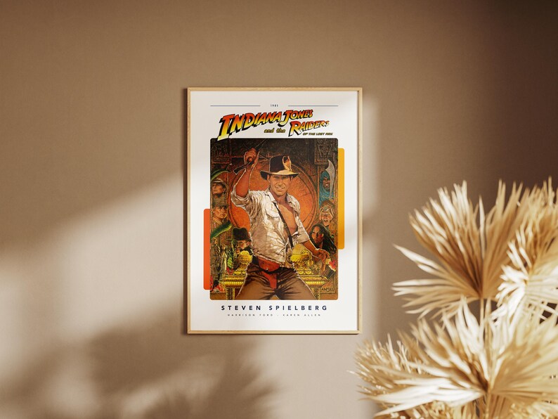 May include: A vintage movie poster for the film "Indiana Jones and the Raiders of the Lost Ark." The poster features a colorful illustration of Indiana Jones holding a whip and standing in front of a temple. The text "Steven Spielberg" is printed at the bottom of the poster.