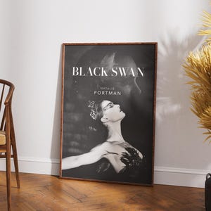 May include: Black and white movie poster for the film "Black Swan" starring Natalie Portman. The poster features a close-up of Portman as a ballerina in a black swan costume.