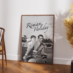 Może przedstawiać: Czarno-biały plakat filmu zatytułowanego "Rzymskie wakacje" z nazwiskiem Williama Wylera u g&oacute;ry. Plakat przedstawia mężczyznę i kobietę jadących skuterem w Rzymie.