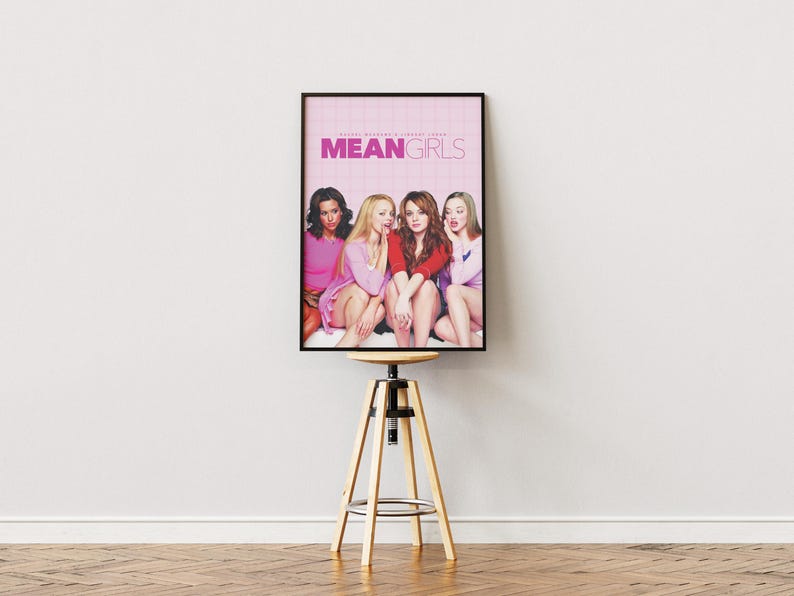 May include: A movie poster for the film "Mean Girls" featuring four young women in pink and red clothing. The poster has a pink background with the title "Mean Girls" in white letters.