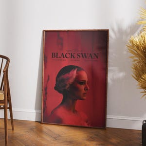 Puede incluir: Un p&oacute;ster de pel&iacute;cula para la pel&iacute;cula "Black Swan" con una mujer con un tocado de plumas blancas, mirando hacia la derecha, sobre un fondo rojo.