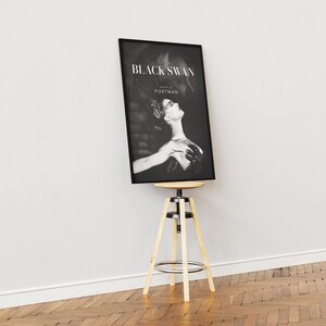 May include: Black and white movie poster for the film "Black Swan" starring Natalie Portman. The poster features a close-up of Portman as a ballerina in a dramatic pose.