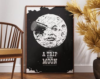 Puede incluir: Un póster en blanco y negro con un diseño retro que presenta la cara de un hombre en la luna. El póster dice "A Trip to the Moon" y "Le Voyage Dans La Lune".