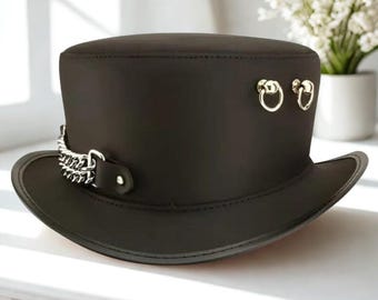 May include: A black top hat with a silver chain and two silver ring accents. The hat has a wide brim and a cylindrical crown. The hat is made of a smooth, dark material.