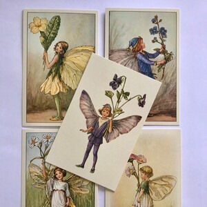 Peut inclure: Ensemble de cinq cartes postales vintage avec des illustrations de fées et de fleurs. Chaque carte représente une fée avec des ailes détaillées, tenant diverses fleurs. La palette de couleurs comprend des verts doux, des jaunes et des violets, créant une esthétique fantaisiste.