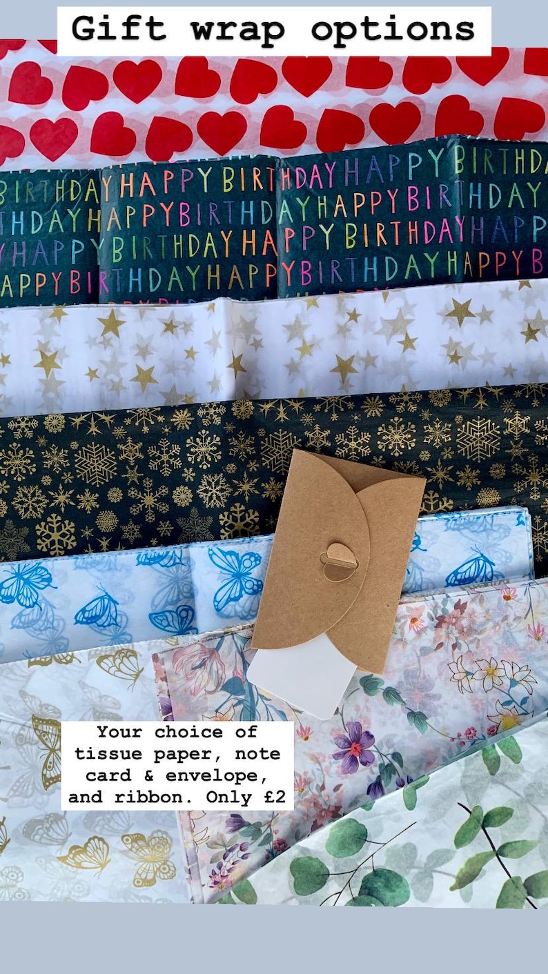 May include: Assortment of gift wrap options including tissue paper with hearts, stars, snowflakes, butterflies, and floral patterns.  A brown envelope is included.  The text reads "Your choice of tissue paper, note card & envelope, and ribbon. Only &pound;2."