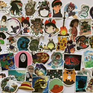 May include: A collection of colourful stickers featuring characters and scenes from popular Japanese animated films, including Totoro, Kiki's Delivery Service, and Spirited Away. The stickers are printed on white paper and have a glossy finish.