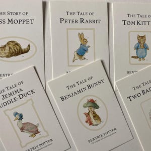 Peut inclure: Six cartes rectangulaires blanches présentant des illustrations et titres de Beatrix Potter : The Story of Miss Moppet, The Tale of Peter Rabbit, The Tale of Tom Kitten, The Tale of Jemima Puddle-Duck, The Tale of Benjamin Bunny et The Tale of Two Bad Mice.
