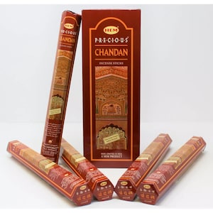 May include: A box of HEM Precious Chandan incense sticks. The box is brown with gold accents and features a traditional Indian design. The sticks are brown and have a hexagonal shape. The text on the box reads "HEM P-R-E-C-I-O-U-S CHANDAN INCENSE STICKS HAND CRAFTED IN INDIA A HEM PRODUCT".
