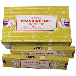 Puede incluir: Una caja amarilla de inciensos Satya Frankincense. La caja tiene una etiqueta azul y blanca con el texto "Satya Frankincense Incense" y "Mrs. Shrinivas "Sugandhalaya (BNG) LLP"". Hay dos cajas más pequeñas de inciensos en la imagen, también con la misma etiqueta.