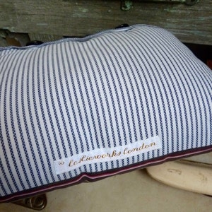 May include: A white and blue striped pillow with a white label that says "leslierworks london".