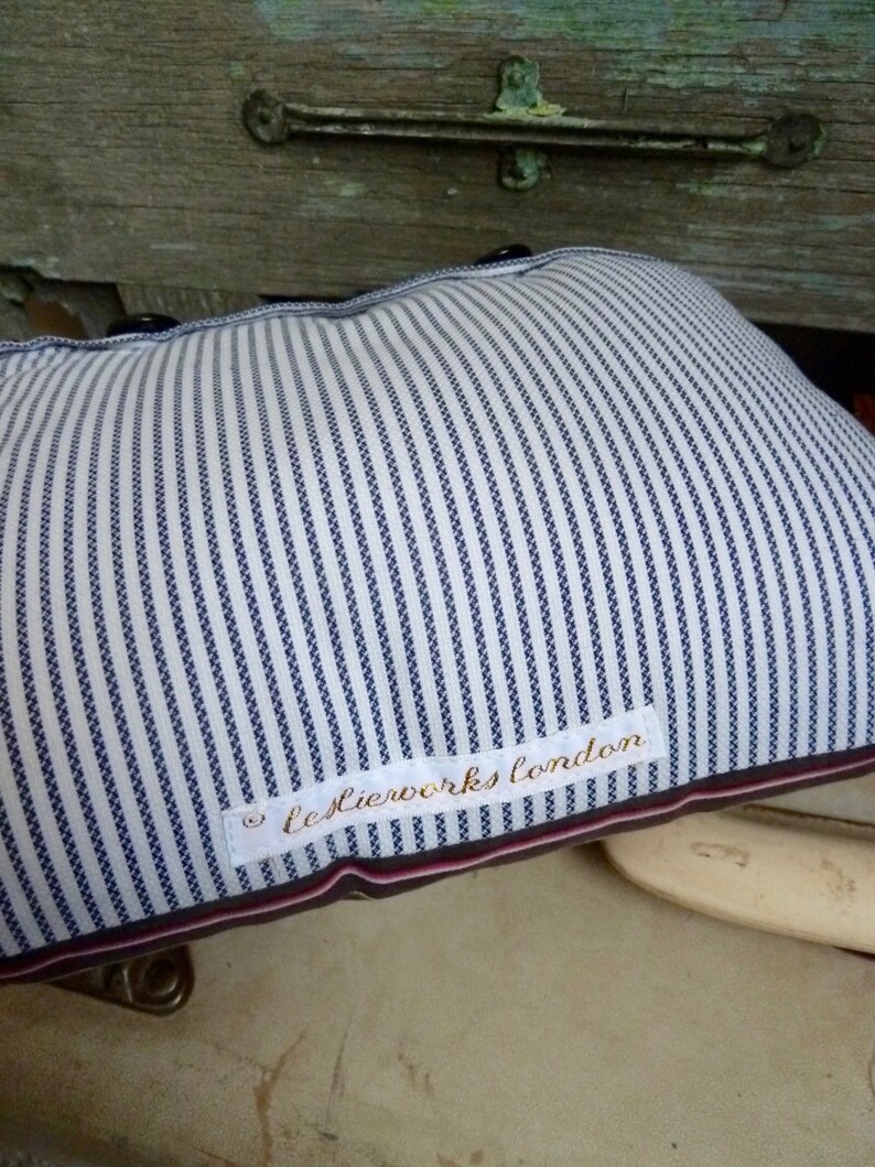 May include: A white and blue striped pillow with a white label that says "leslierworks london".