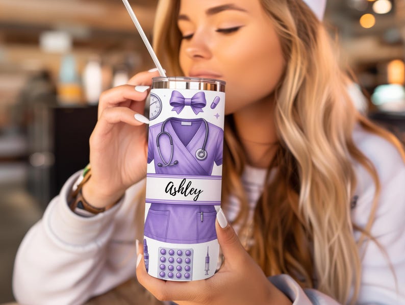 May include: A purple and white stainless steel tumbler with a design of a nurse's uniform, a stethoscope, a syringe, and pills. The name "Ashley" is written on the tumbler.