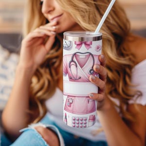 Puede incluir: Un vaso de acero inoxidable con un dise&ntilde;o rosa y blanco que presenta un estetoscopio, un uniforme de enfermera y otros s&iacute;mbolos m&eacute;dicos. El vaso tiene una tapa y una pajita.