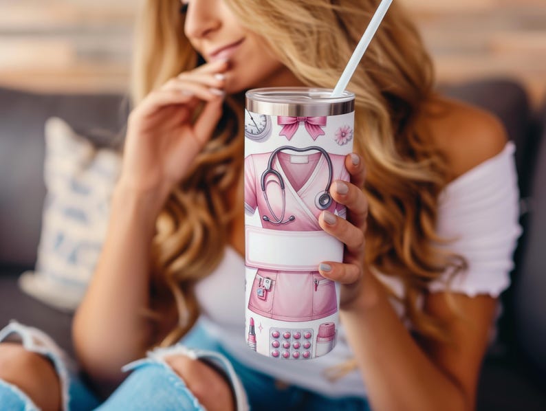 Puede incluir: Un vaso de acero inoxidable con un dise&ntilde;o rosa y blanco que presenta un estetoscopio, un uniforme de enfermera y otros s&iacute;mbolos m&eacute;dicos. El vaso tiene una tapa y una pajita.