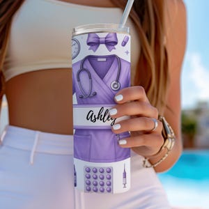 May include: A purple and white stainless steel tumbler with a personalised name "Ashley" and a design of a nurse's uniform, stethoscope, pills, and a syringe.
