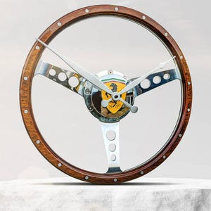 May include: A wooden steering wheel clock with a chrome center and a Ferrari logo. The clock hands are set to 10:10.