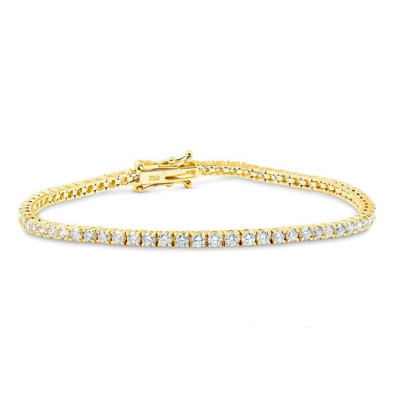 May include: A gold tennis bracelet with a clasp, set with numerous small, clear gemstones. The bracelet is made of gold and features a delicate design. The clasp is also gold and is marked with the number 750.
