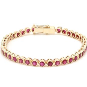 Könnte beinhalten: Ein goldfarbenes Armband mit einer Reihe von runden, leuchtend roten Edelsteinen. Die Edelsteine sind eng aneinander gesetzt und bilden eine durchgehende Farblinie. Das Armband hat einen sicheren Verschluss.