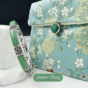 May include: A silver bracelet with rectangular jade stones and floral accents, next to a teal clutch with a floral pattern and a jade clasp. The text "Jade+1Bag" is at the bottom.