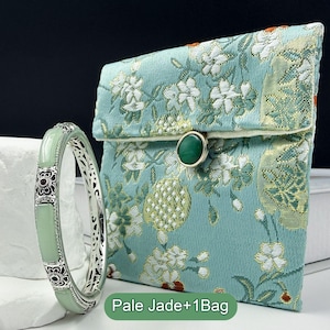 May include: A pale green jade bracelet with ornate silver detailing and a matching floral-patterned pouch. The pouch is teal with white and gold floral designs and a green stone clasp. The text "Pale Jade+1Bag" is at the bottom.