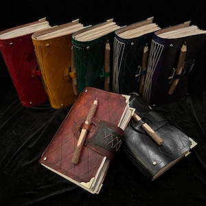 May include: A collection of leather-bound journals in various colors, including red, yellow, green, black, and purple. Each journal features a unique diamond-stitched pattern and a wooden pencil secured with a leather strap. The journals are open, revealing the pages.