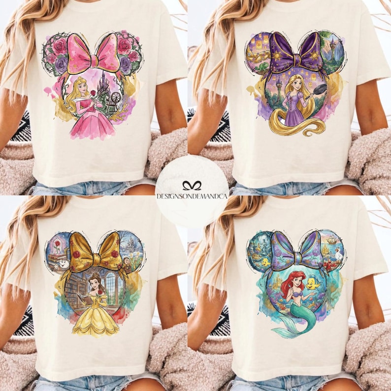Puede incluir: Camisetas color crema con dise&ntilde;os de princesas de Disney dentro de siluetas de orejas de Mickey Mouse. Cada dise&ntilde;o muestra una princesa diferente: Aurora, Rapunzel, Bella y Ariel. Las camisetas tienen gr&aacute;ficos estilo acuarela con colores vibrantes y el texto "DESIGNSONDEMANDCA".