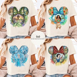 Puede incluir: Cuatro camisetas color crema con dise&ntilde;os de personajes de Disney dentro de siluetas de orejas de Mickey Mouse. Los dise&ntilde;os incluyen a Tiana, Moana, Elsa y Blancanieves. El texto "DESIGNSONDEMANDCA" es visible en un c&iacute;rculo blanco.