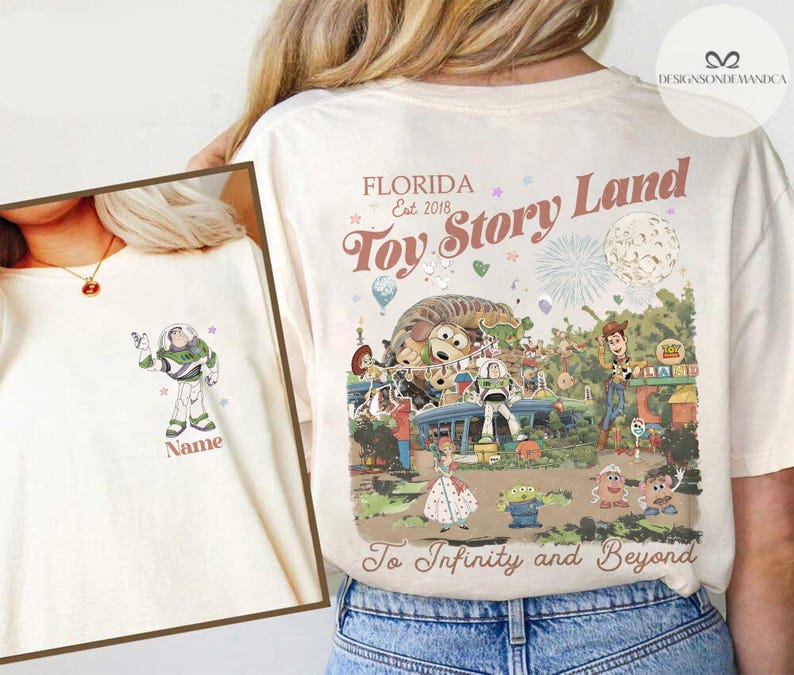 Puede incluir: Camiseta color crema con un gr&aacute;fico colorido de los personajes de Toy Story en Toy Story Land en Florida. La camiseta incluye el texto "Toy Story Land" y "To Infinity and Beyond."