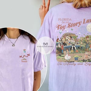 Puede incluir: Camiseta lila claro con un dibujo animado de Forky en la parte delantera. La parte trasera tiene un gr&aacute;fico de Toy Story Land con el texto "Florida Est. 2018 Toy Story Land To Infinity and Beyond."