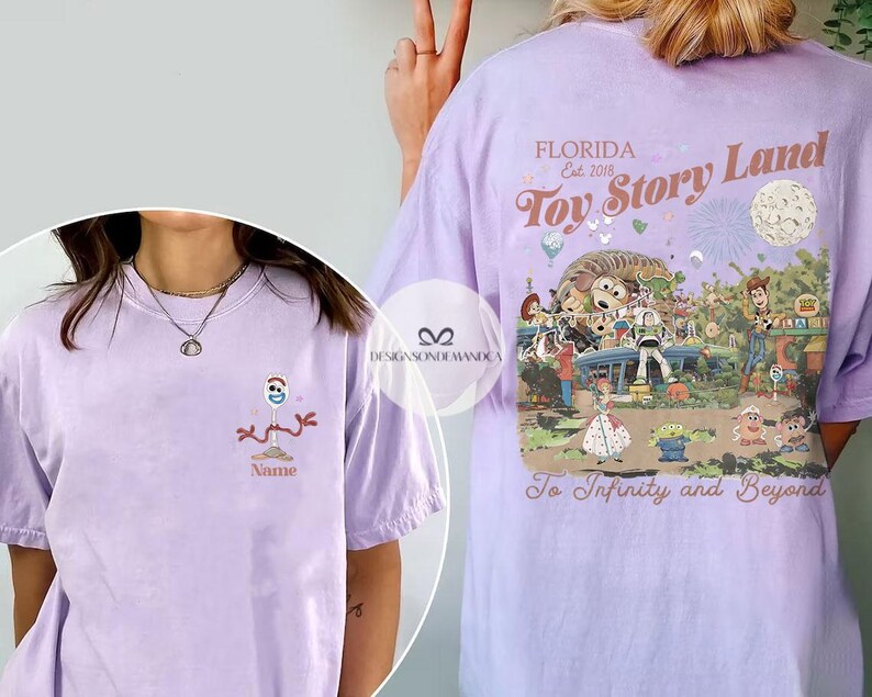 Puede incluir: Camiseta lila claro con un dibujo animado de Forky en la parte delantera. La parte trasera tiene un gr&aacute;fico de Toy Story Land con el texto "Florida Est. 2018 Toy Story Land To Infinity and Beyond."