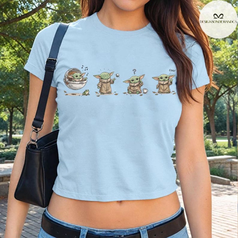May include: Light blue crop top featuring a graphic of a character in various poses. The character is depicted in a series of four images, each showing a different action. The word "Cool" is written on the shirt.