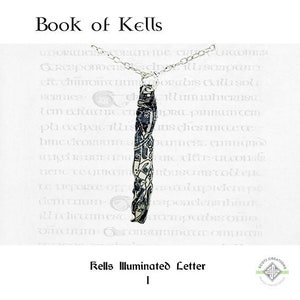 May include: A silver necklace with a pendant featuring a detailed black and white illustration of a Celtic knot design. The pendant is shaped like a long, thin rectangle. The text "Book of Kells" and "Rells Illuminated Letter" is visible in the image.