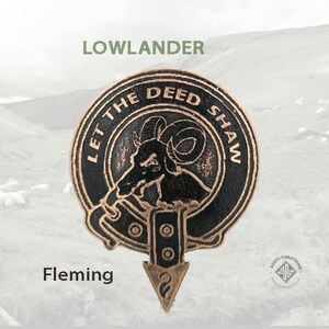 May include: A bronze-coloured metal pin with a black and white image of a ram's head with the text "Let the Deed Shaw" around the image. The pin is a Lowlander Fleming clan crest.