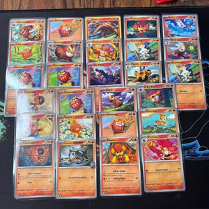 May include: A white ceramic mug with a black handle and the text "But First, Coffee" in a bold, black font. The mug is set against a blurred background, suggesting a cozy setting.