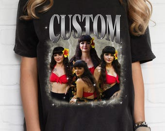 May include: A black short-sleeve t-shirt featuring a graphic print with the word CUSTOM in a metallic font. The design includes three images of a person with dark hair and a yellow flower, wearing a red bikini top, set against a lightning background.