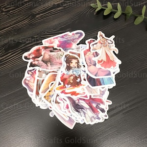 Könnte beinhalten: Eine Sammlung bunter Anime-Charakter-Aufkleber mit weißen Rändern. Die Aufkleber zeigen verschiedene Charaktere mit unterschiedlichen Frisuren, Kleidung und Posen. Die Aufkleber befinden sich auf einer dunkelbraunen Holzoberfläche.