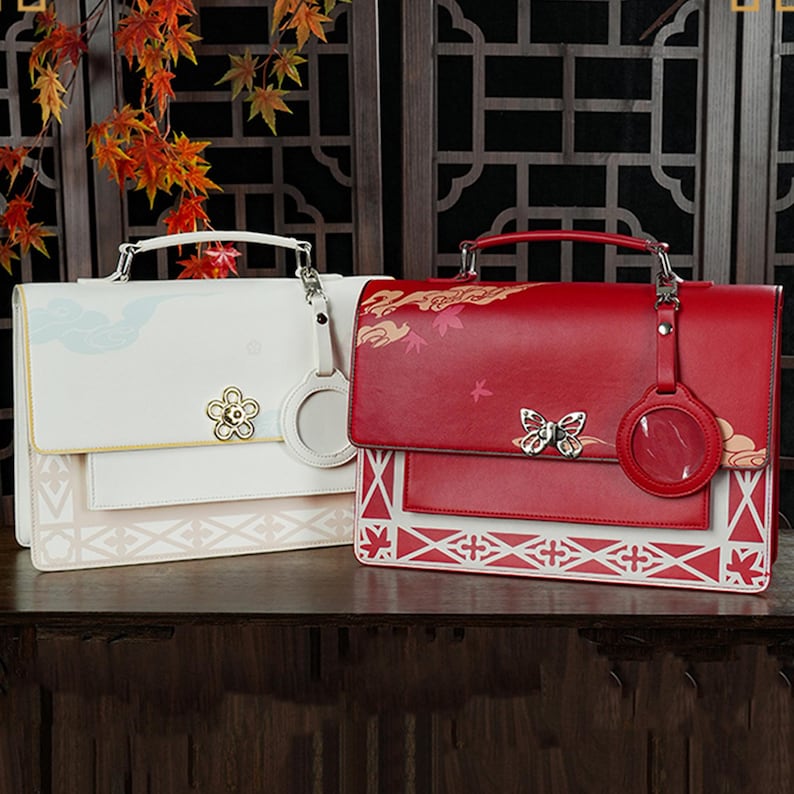 Pu&ograve; includere: Due eleganti borse a mano con motivi floreali. Una &egrave; bianca con un design floreale blu chiaro e l'altra &egrave; rossa con un design floreale rosso e bianco. Entrambe hanno un ciondolo a farfalla argentato e un ciondolo a cerchio argentato.
